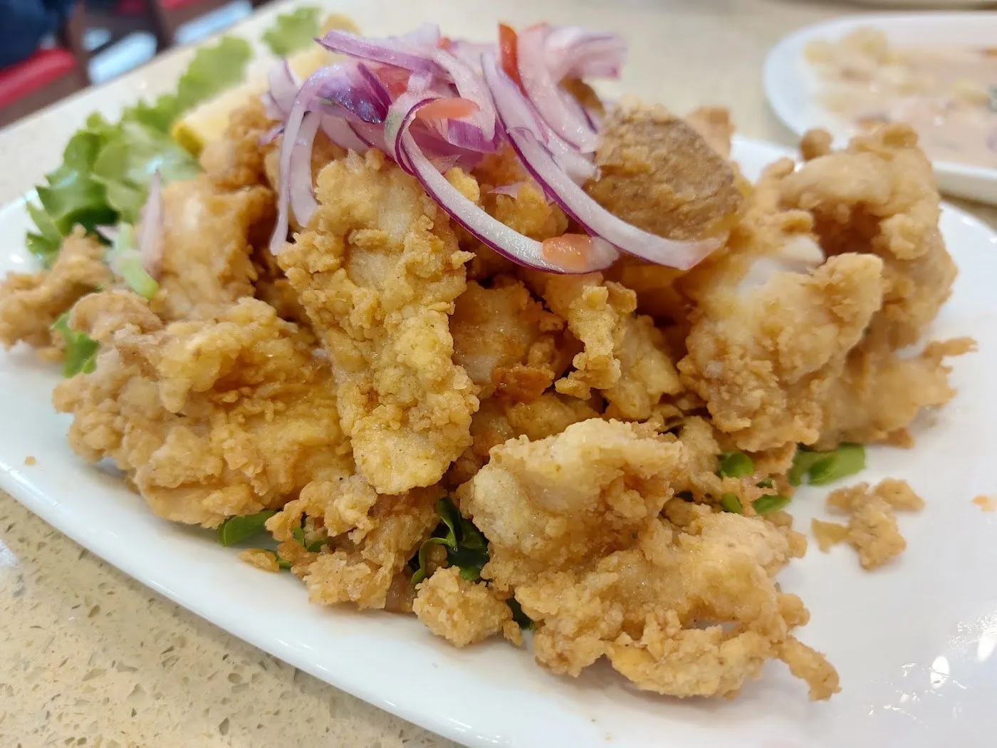 Pescado frito rebozado con cebolla morada por encima